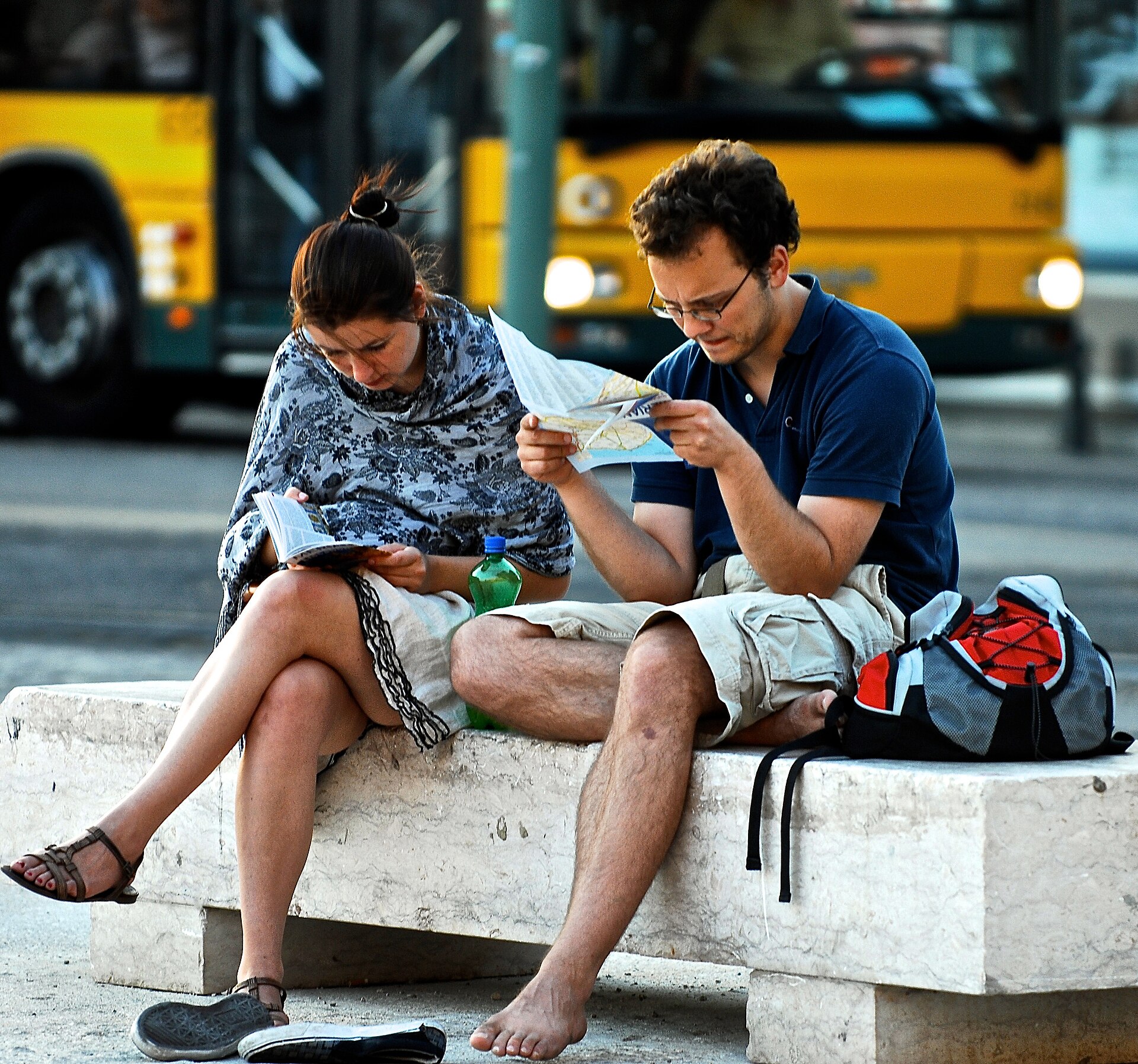 Two travellers consulting maps while seated outdoors