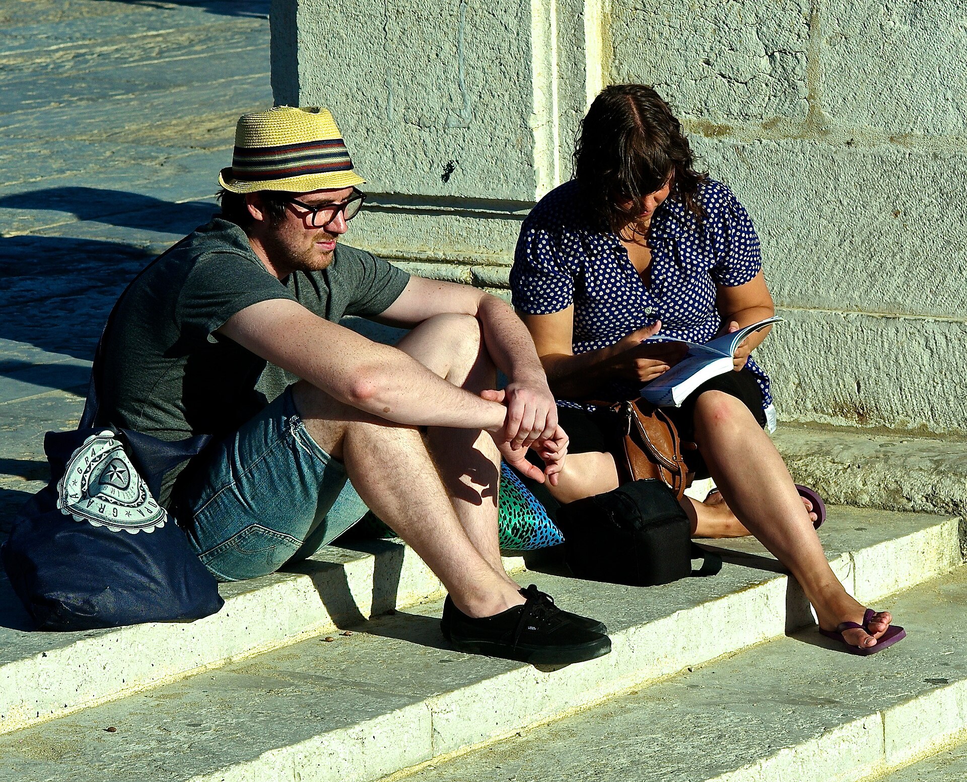 Two travellers consulting a guide while seated on steps