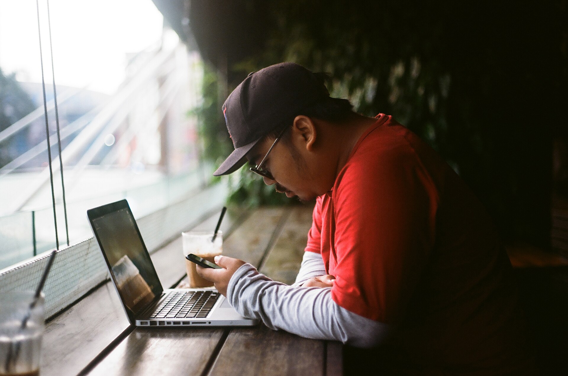 A person using a laptop and phone at a cafe