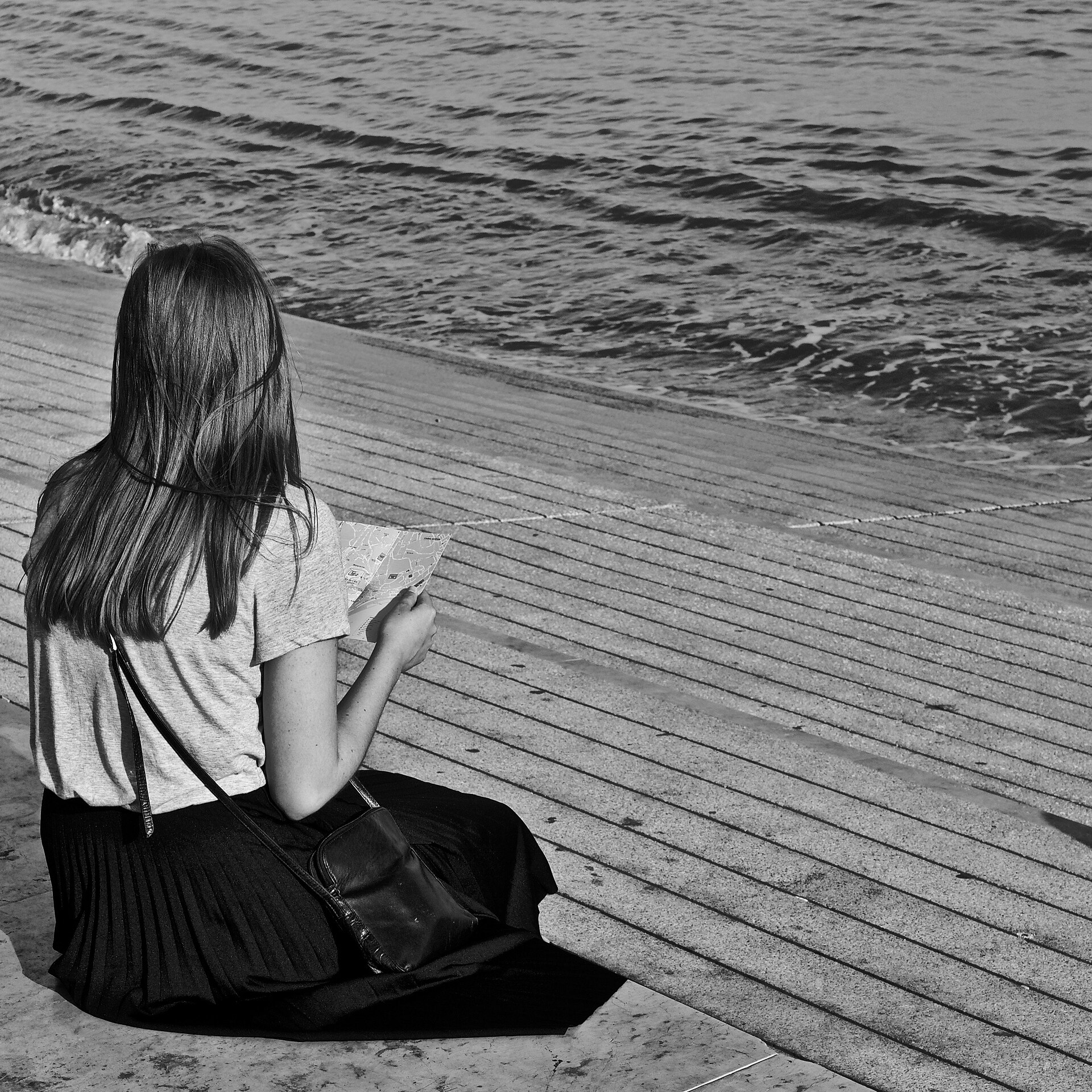A traveller sitting beside the Tagus River with a Lisbon map