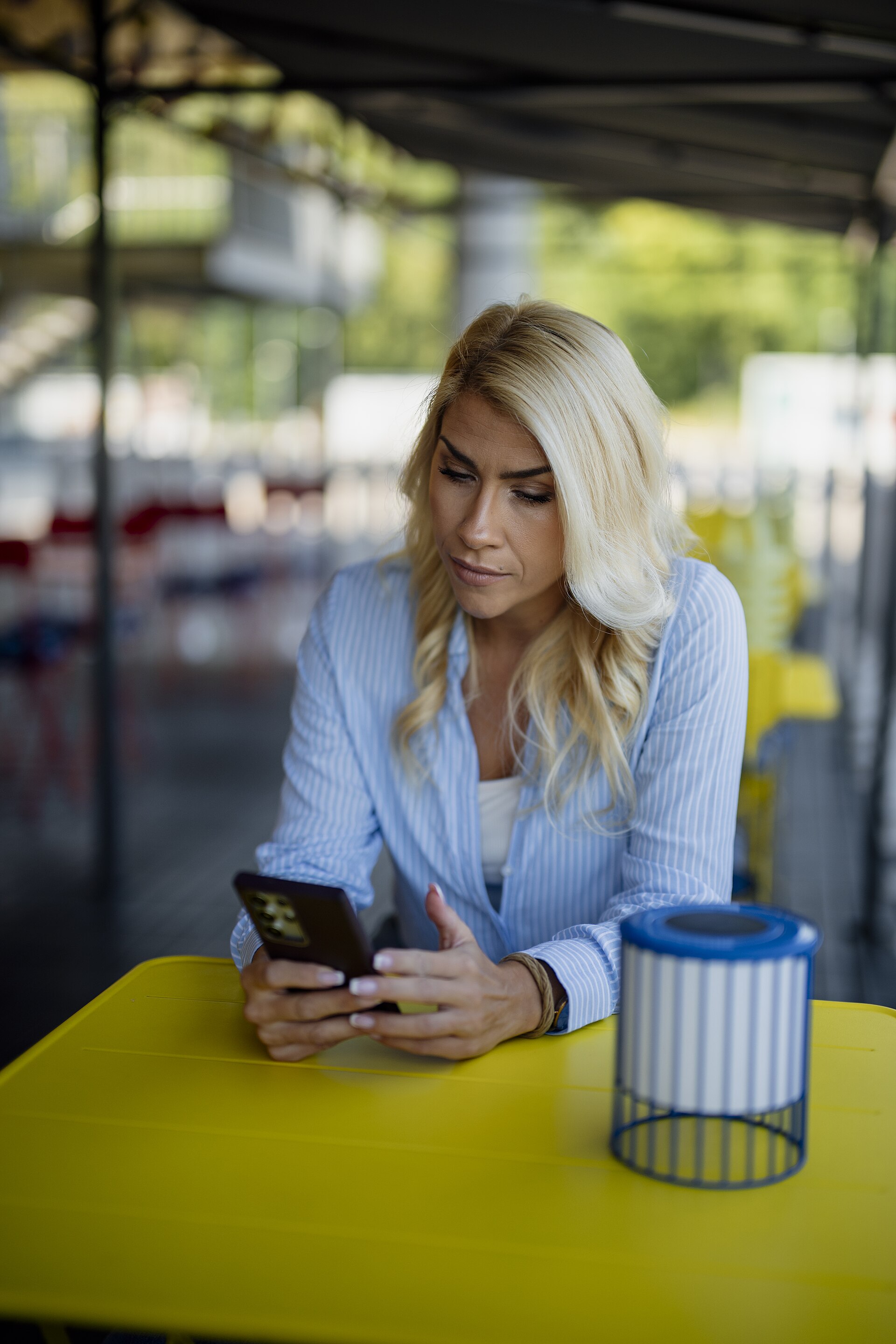 A woman checking a smartphone at an outdoor cafe table