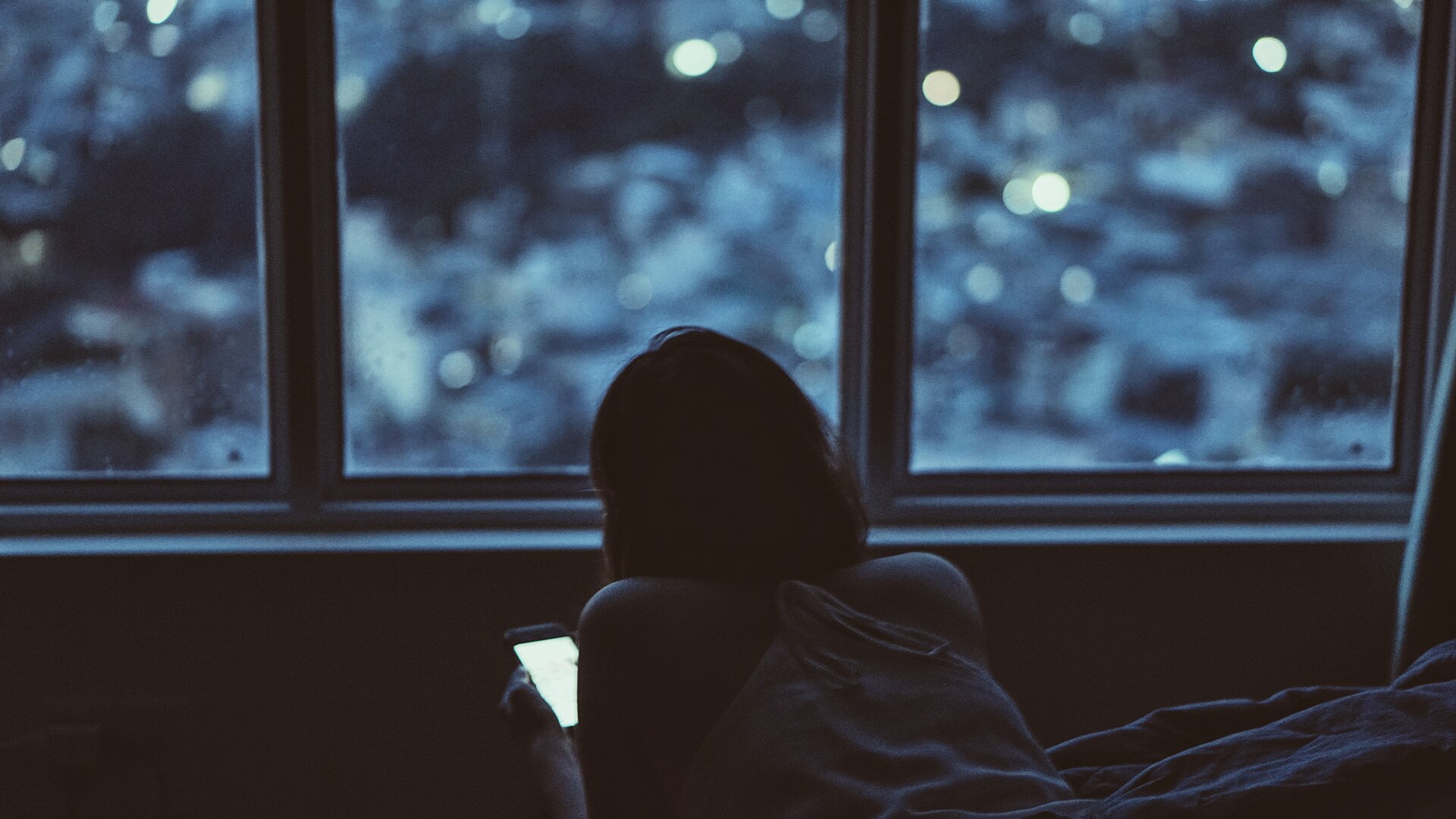 A person using a phone beside a window