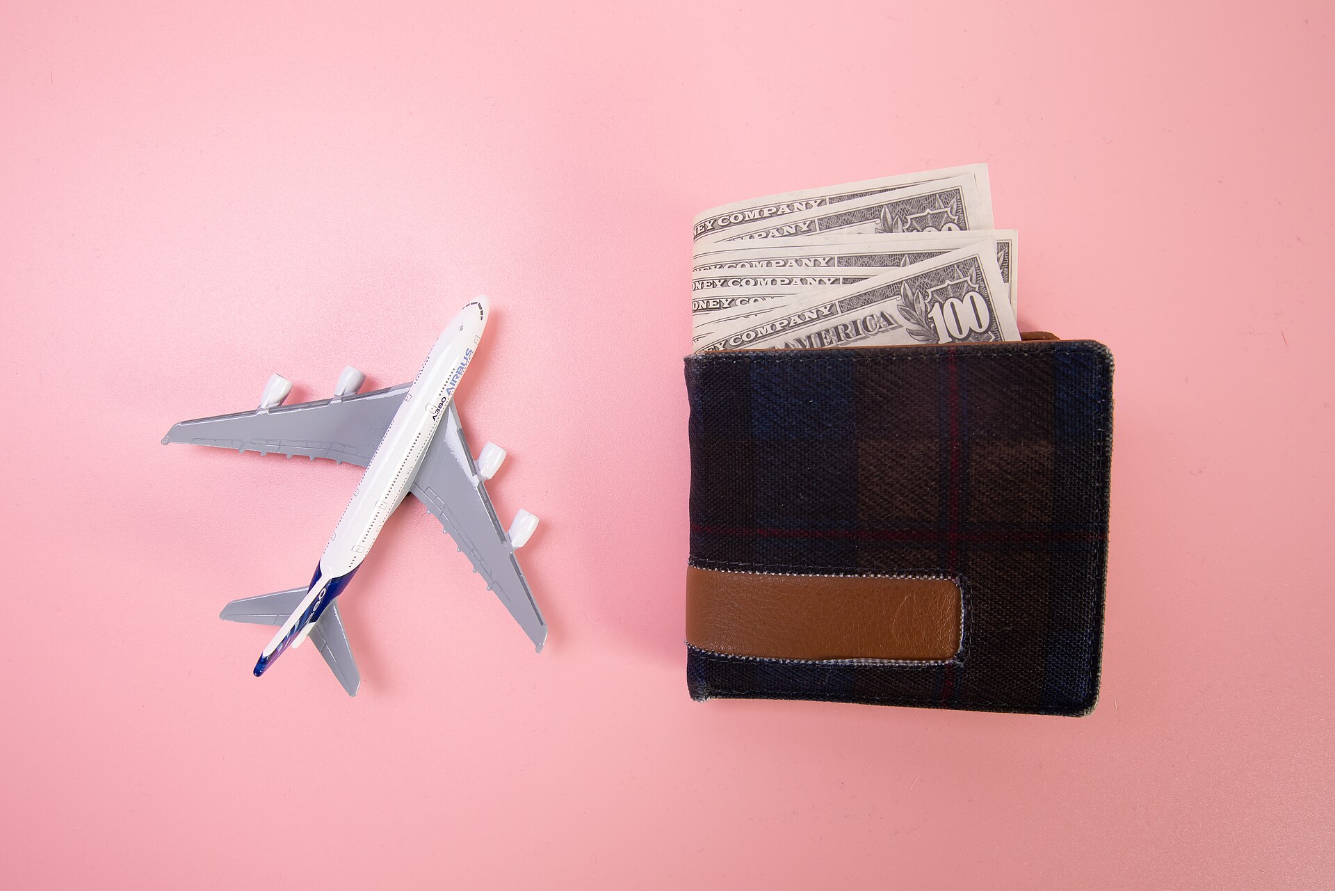A wallet with banknotes beside a model aeroplane