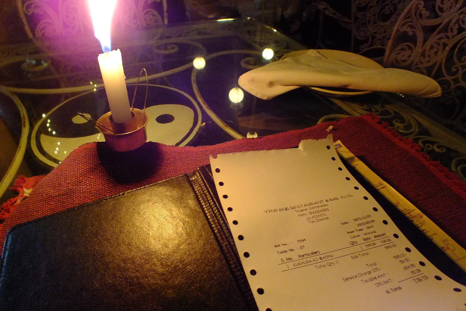 A restaurant bill beside a candle on a table in Kathmandu