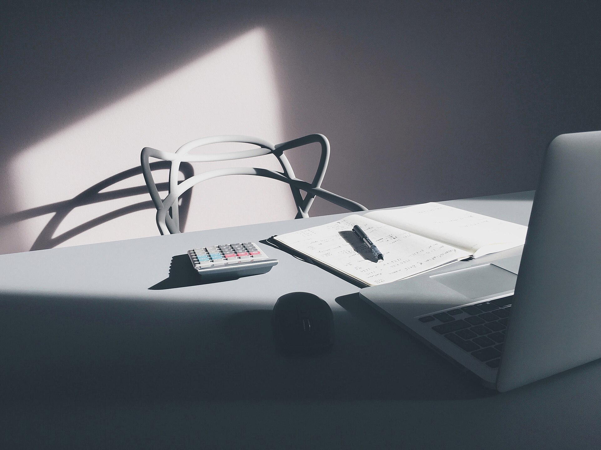 A calculator, notebook and laptop on a desk