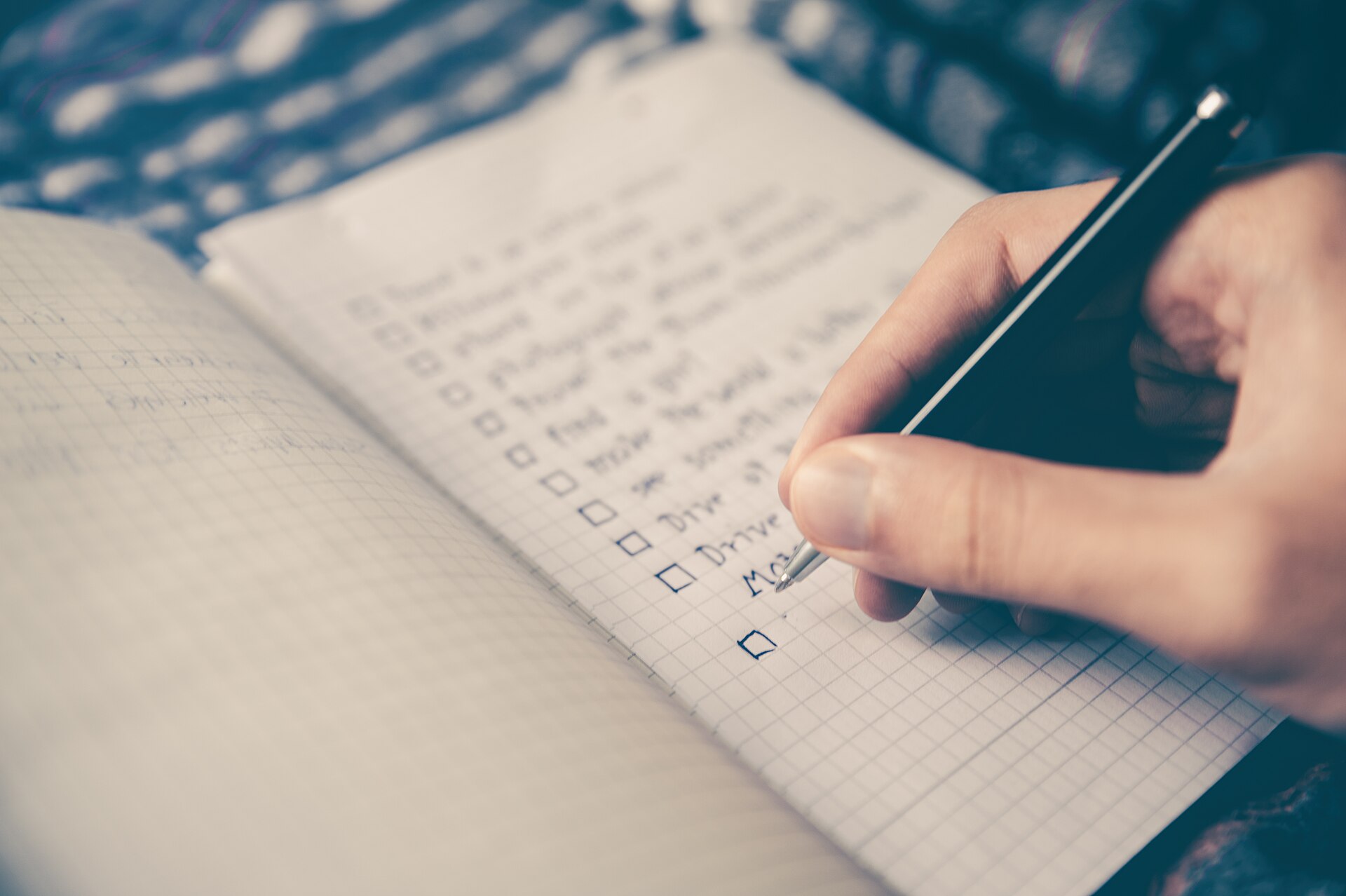A hand adding items to a notebook checklist