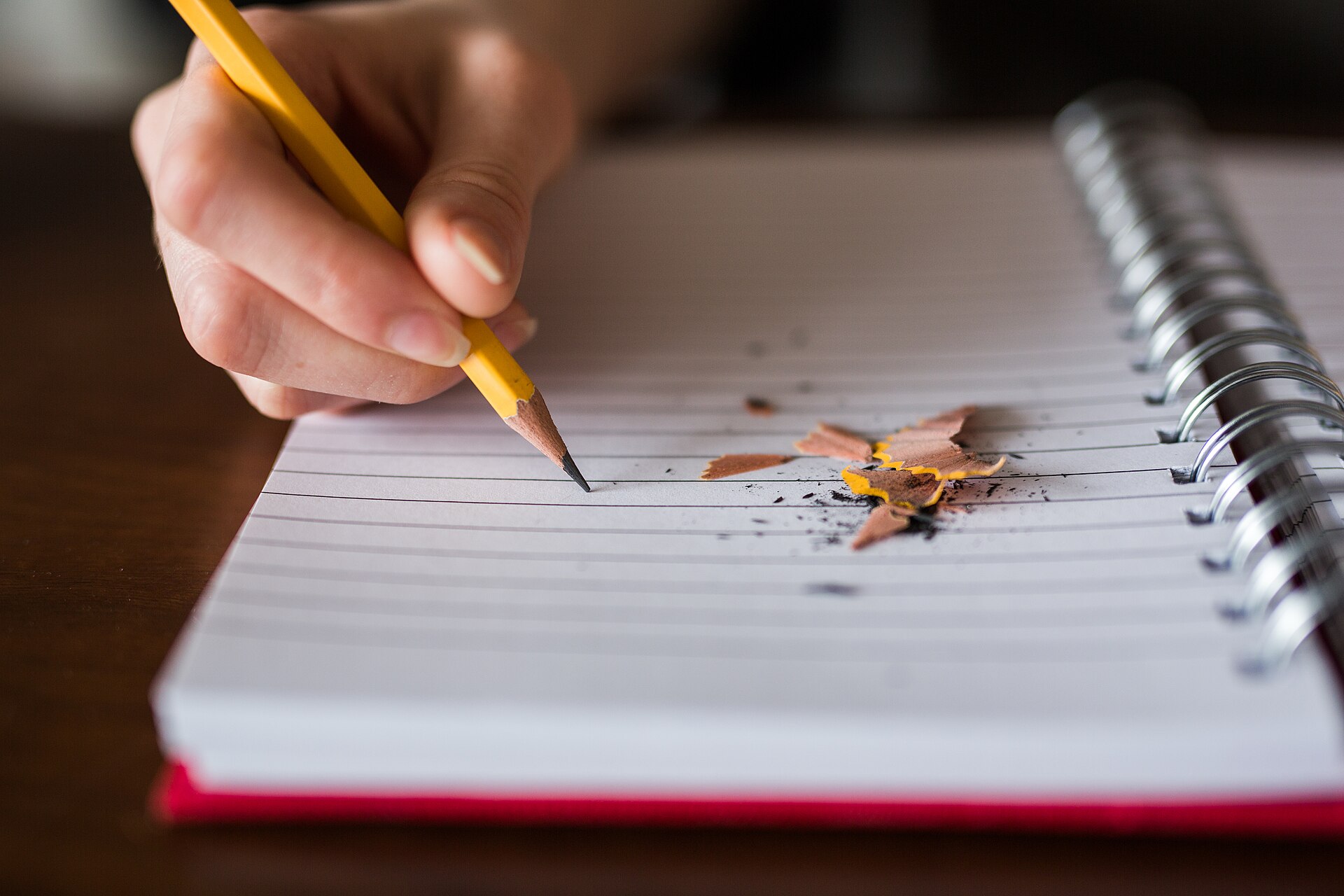 A person writing with a pencil in a notebook